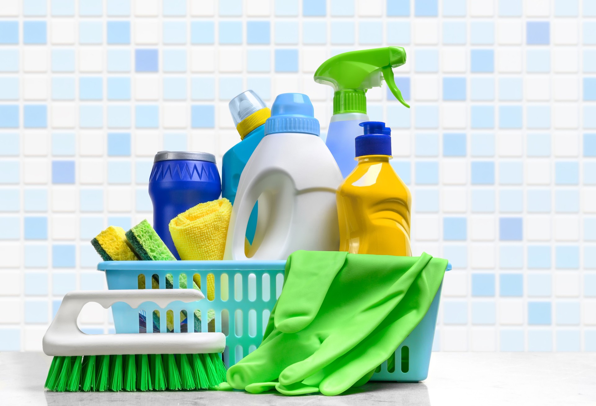 Cleaning supplies in plastic box on white table in the bathroom